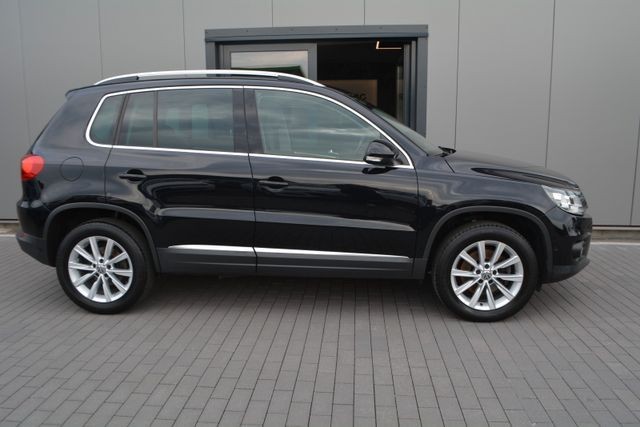 Side view of a black SUV parked on a gray paved surface in front of a modern building.