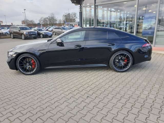 Sleek black sports car parked in front of a dealership with reflective glass windows.