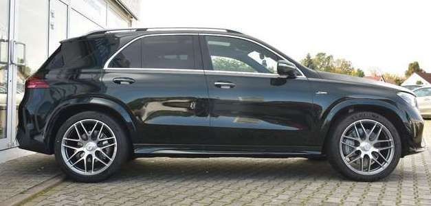 Side view of a black luxury SUV parked on a cobblestone driveway.